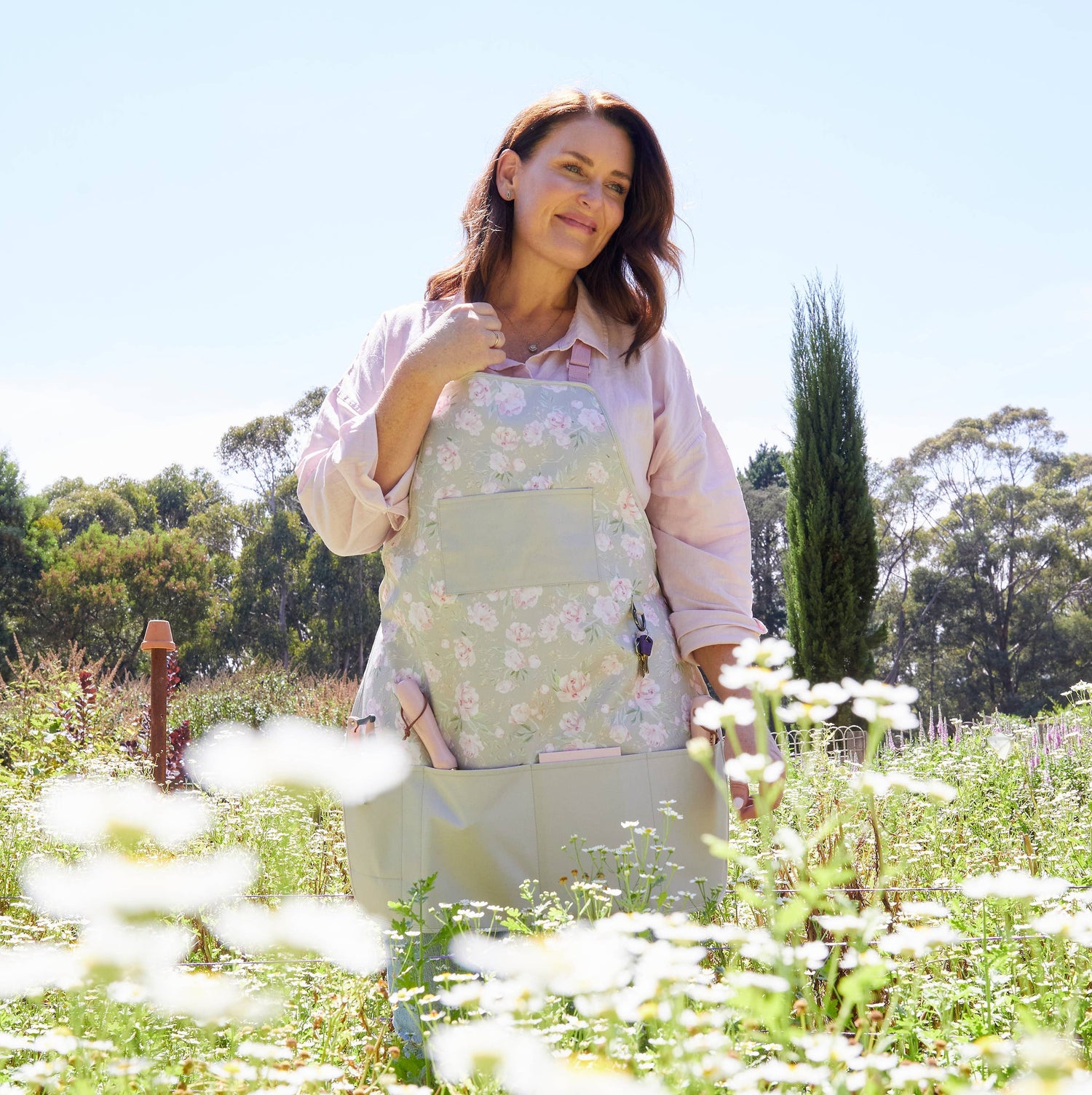 Woman in a garden wearing a floral apron among white flowers