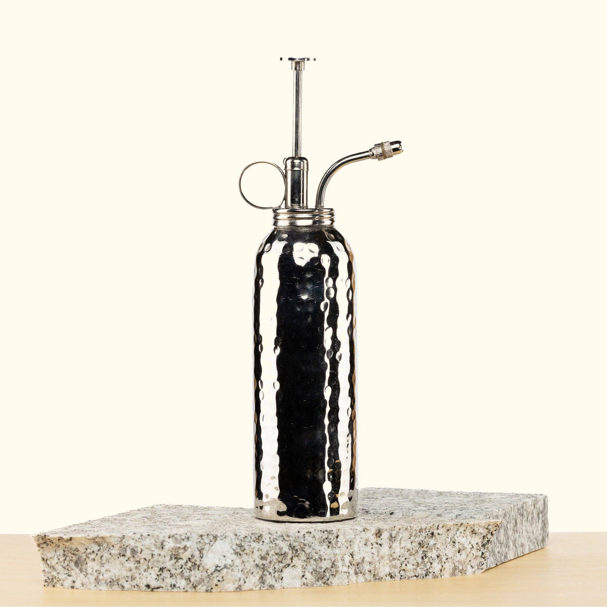 Silver Metal Plant mister on a stone surface with a white background