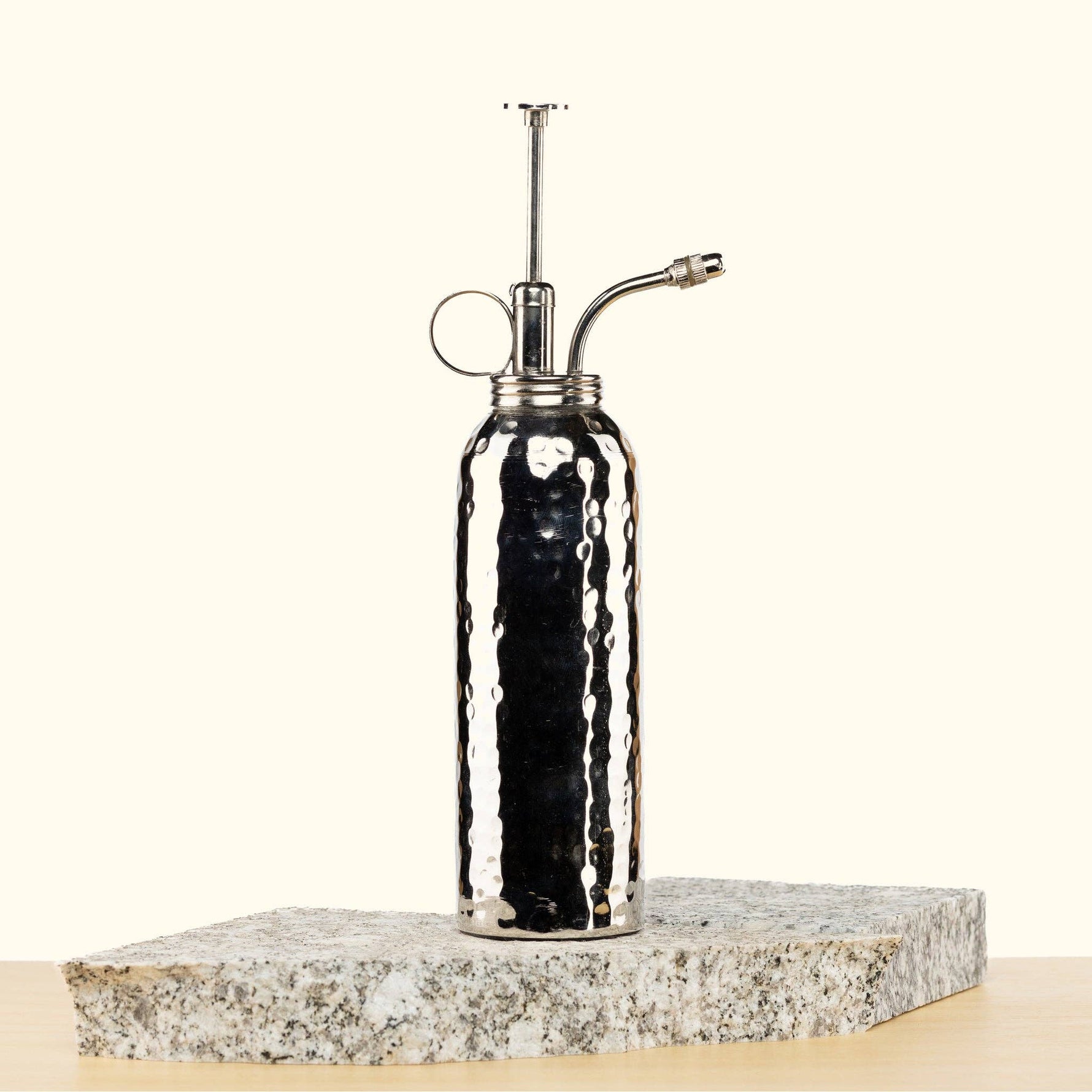Silver Metal Plant mister on a stone surface with a white background