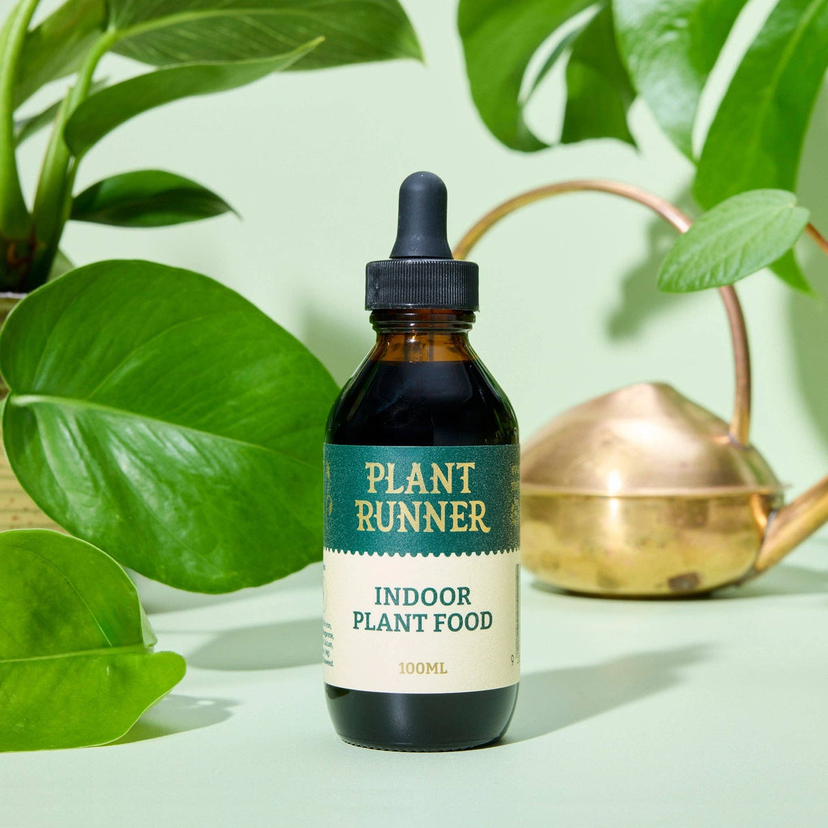 Bottle of Plant Runner indoor plant food with green leaves in the background