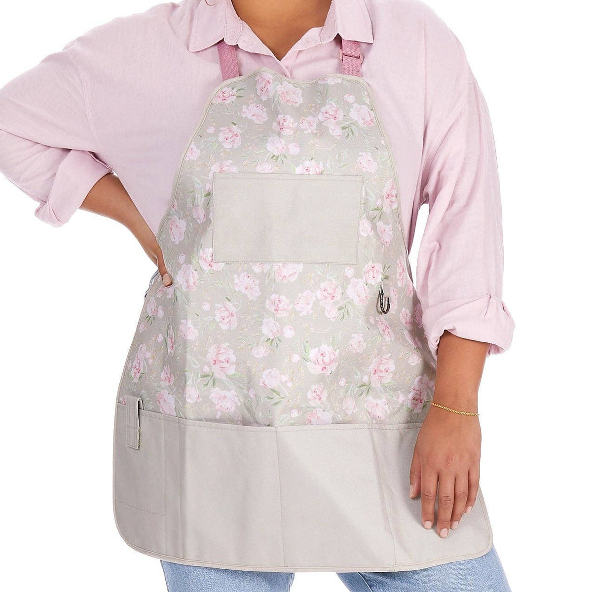 Person wearing a floral gardening apron over a pink shirt on a white background