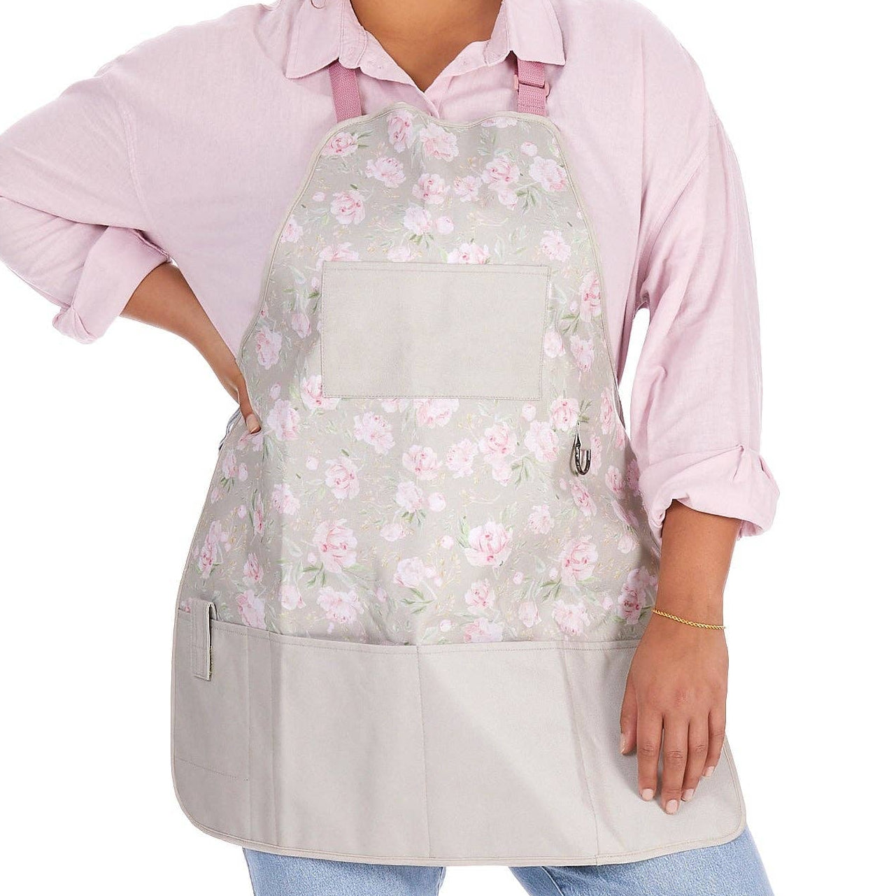 Person wearing a floral gardening apron over a pink shirt on a white background